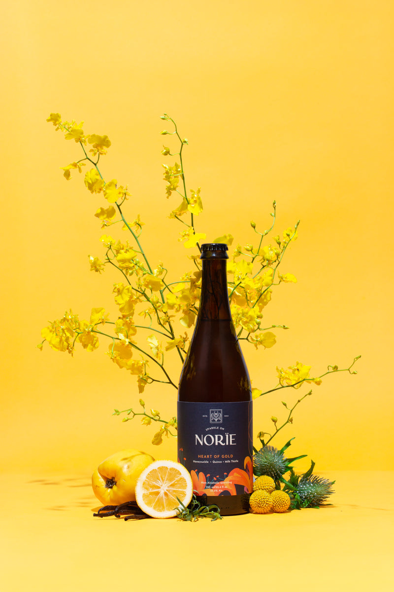Norïe Heart of Gold bottle styled with yellow flowers and botanical ingredients