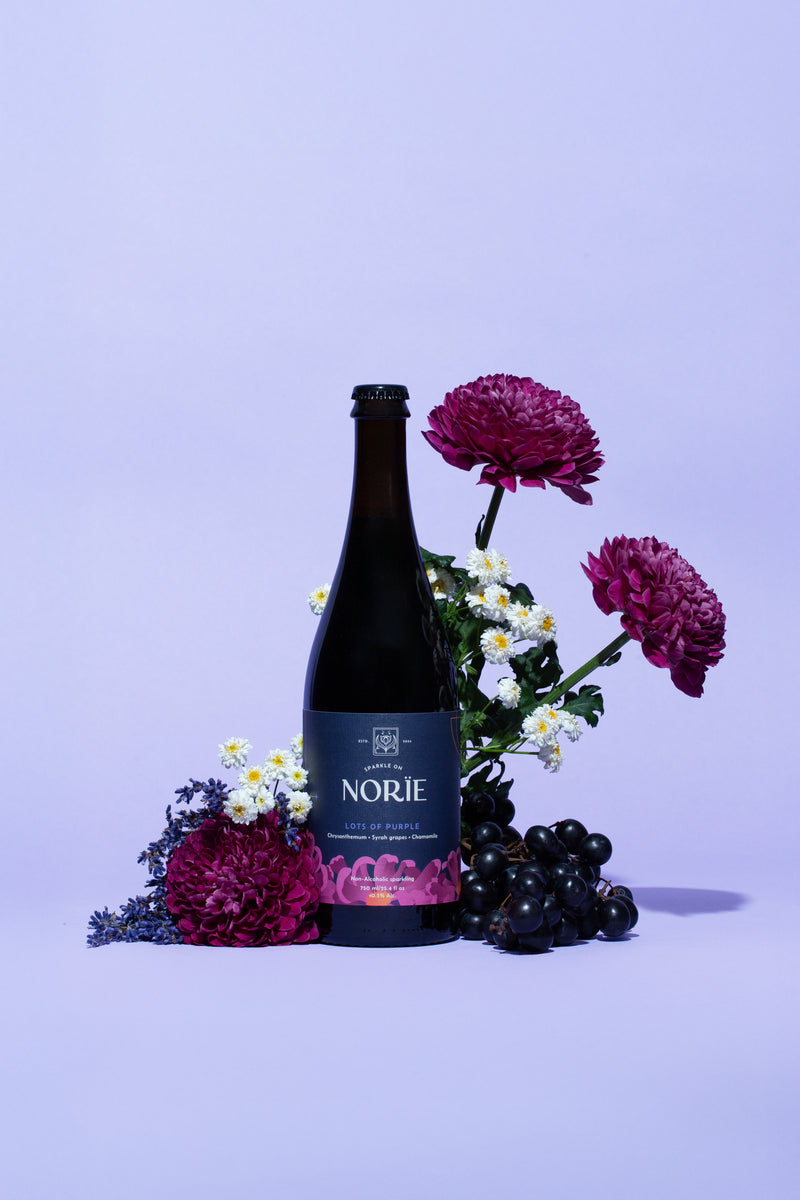 Norïe Lots of Purple bottle styled with flowers and grapes in a purple background