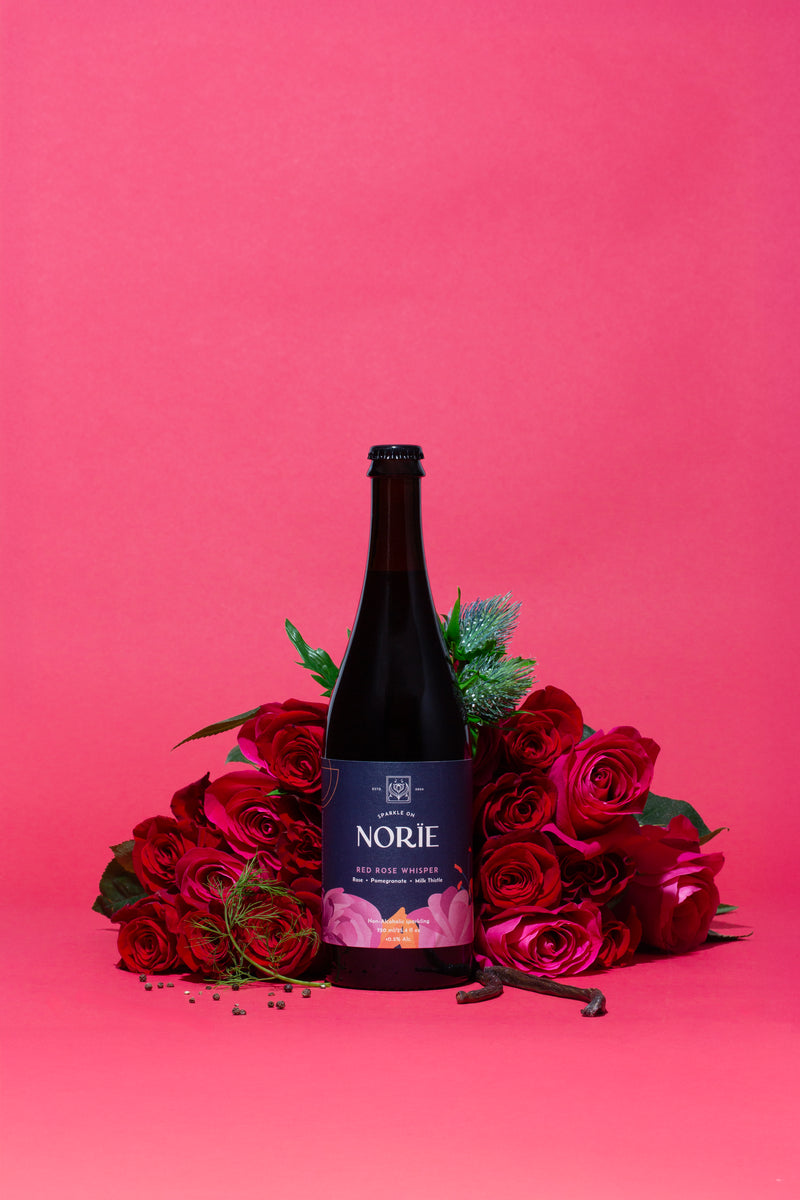 Norïe Red Rose Whisper bottle styled with red roses and floral botanicals