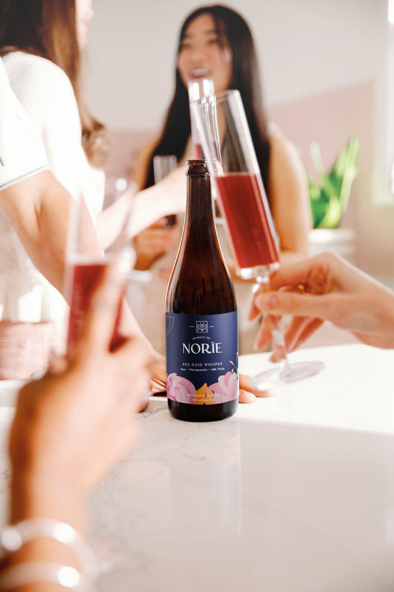 People toasting at a table with Norïe Red Rose Whisper non-alcoholic sparkling drink